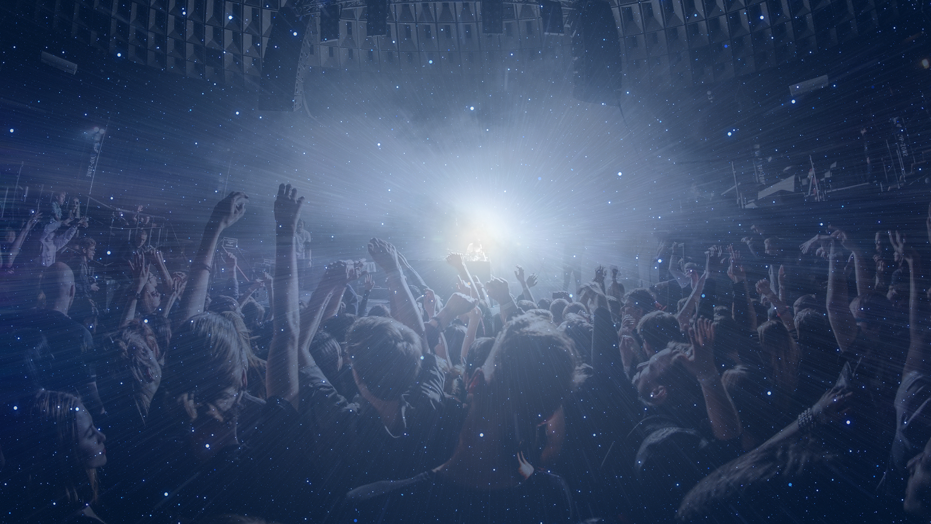 Festival crowd with hands raised under stage lights